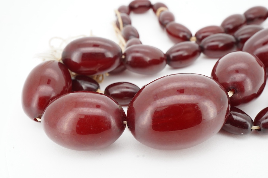 A cherry-coloured bakelite imitation amber necklace, composed of graduated oval beads measuring approximately 1.2-3cm, length 56cm, gross weight approximately 54 grams